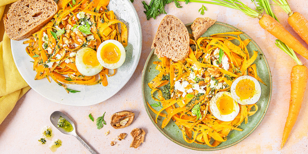 Tallarines de zanahoria con pesto y huevo mollet servidos en dos platos